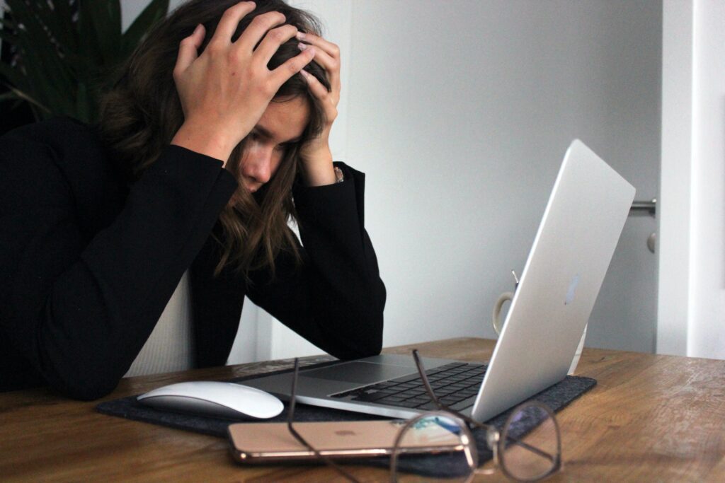 A woman with her head in her hands looking at her laptop, wondering can an iva stop bailiffs