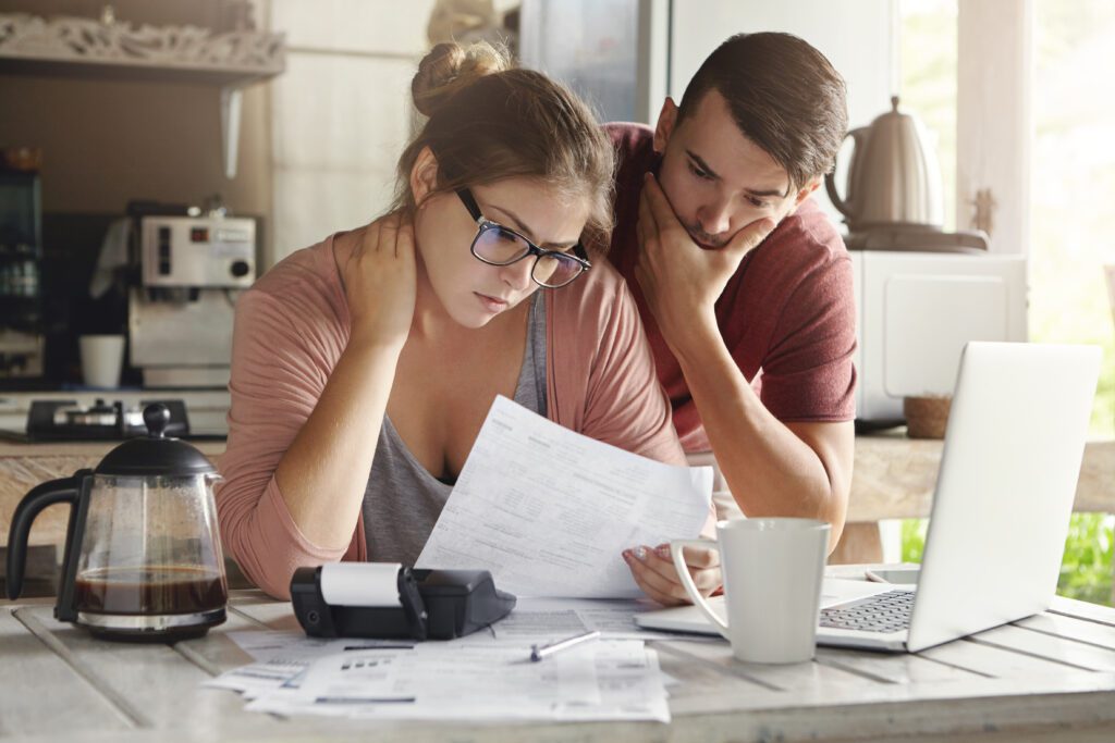 A man and a woman looking at their debts, debating a debt management plan vs iva