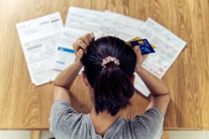 Woman-holding-credit-cards-with-head-in-hands-reading-debt-letters