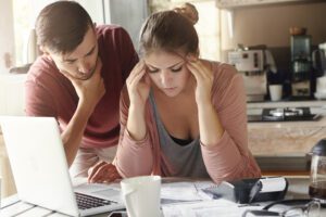 Young-couple-reading-debt-letters-next-to-laptop